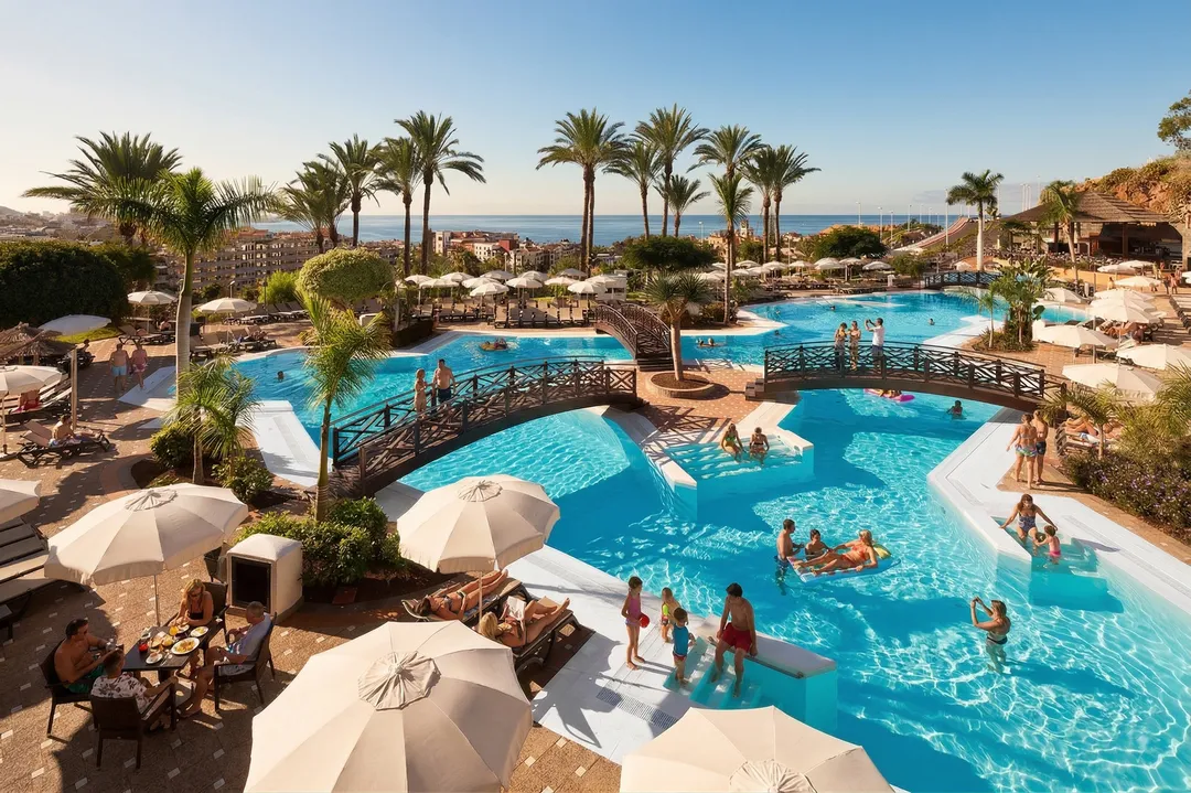 Familias disfrutando de la piscina de hotel de tenerife en su viaje todo incluido con la Marquita Viajera